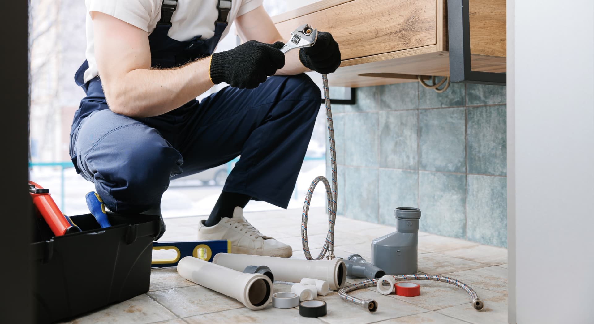 Plumber working on pipe fittings beneath a bathroom basin