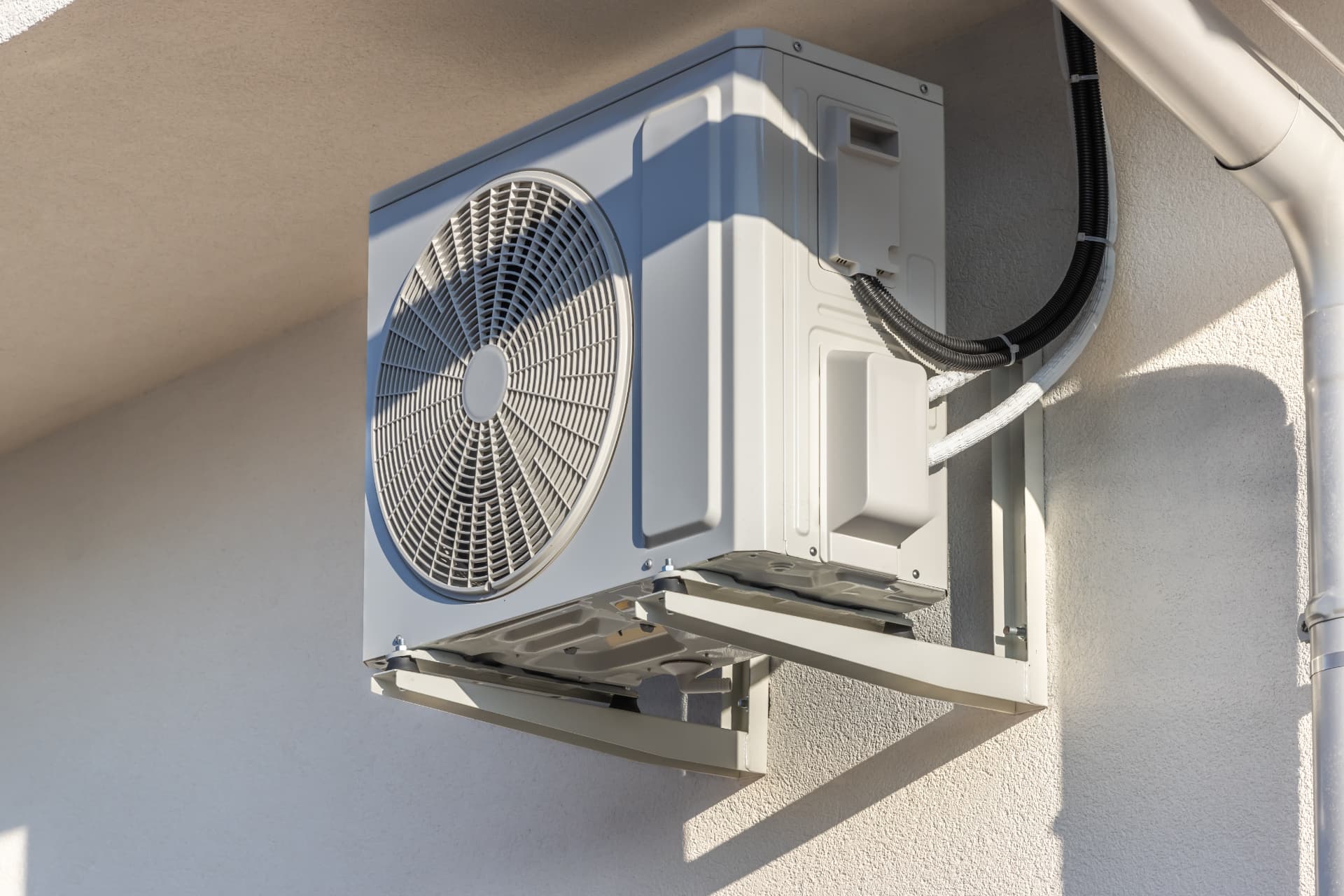 Outdoor air source heat pump mounted beside a home